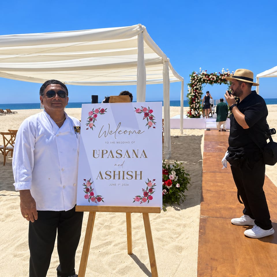 Chef beside a beach wedding welcome sign