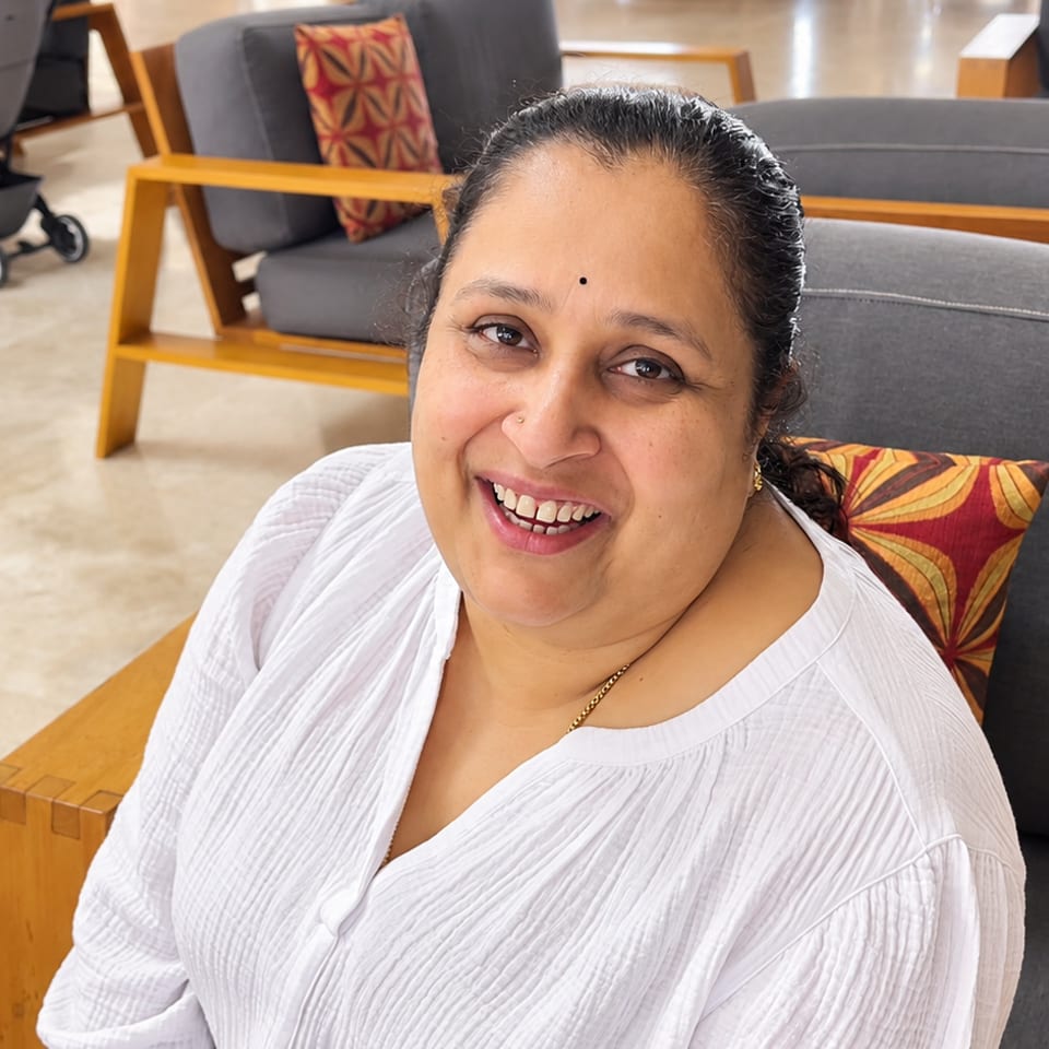 Smiling guest in a white blouse seated in a cushioned lounge chair