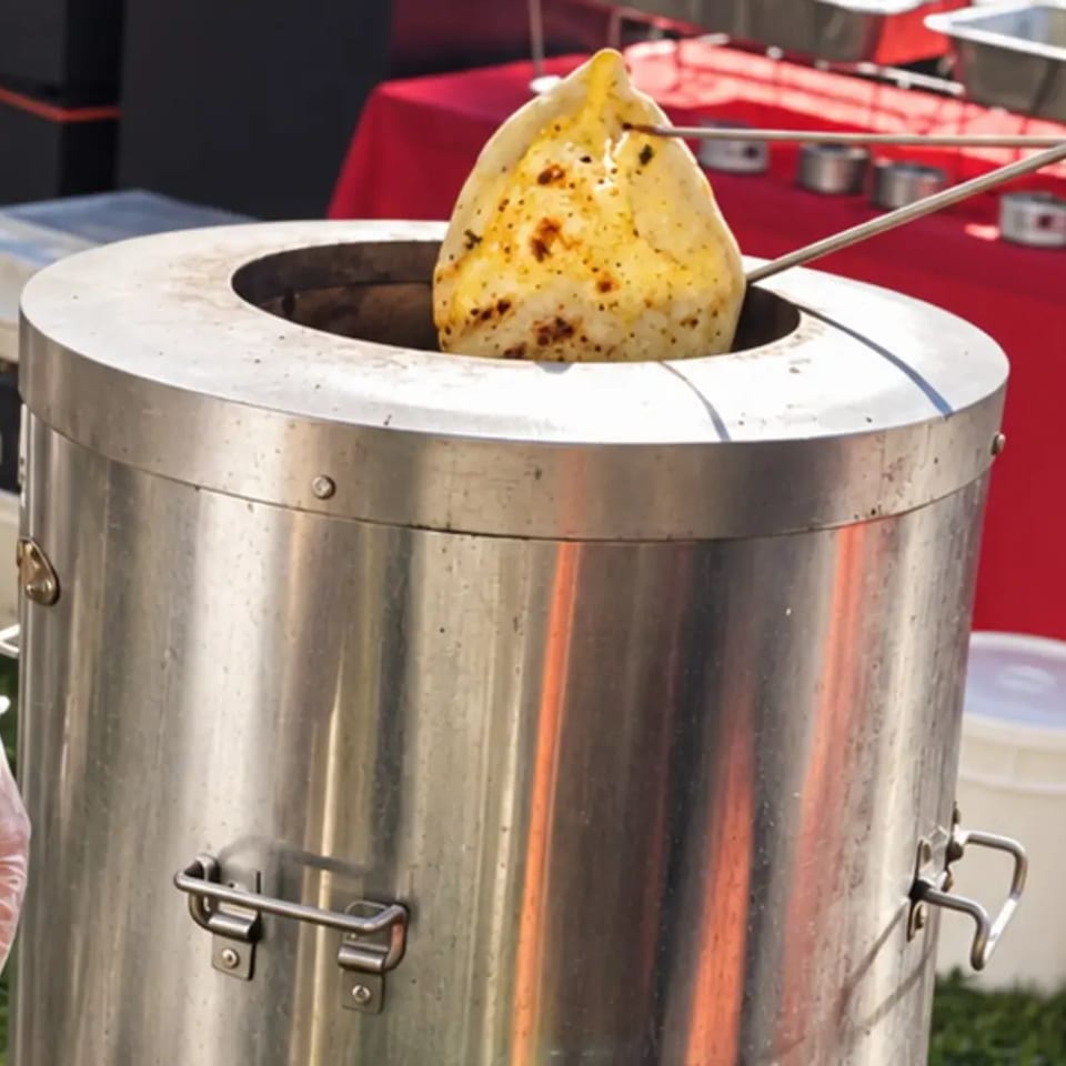 Fresh naan lifted from a live tandoor at an outdoor event