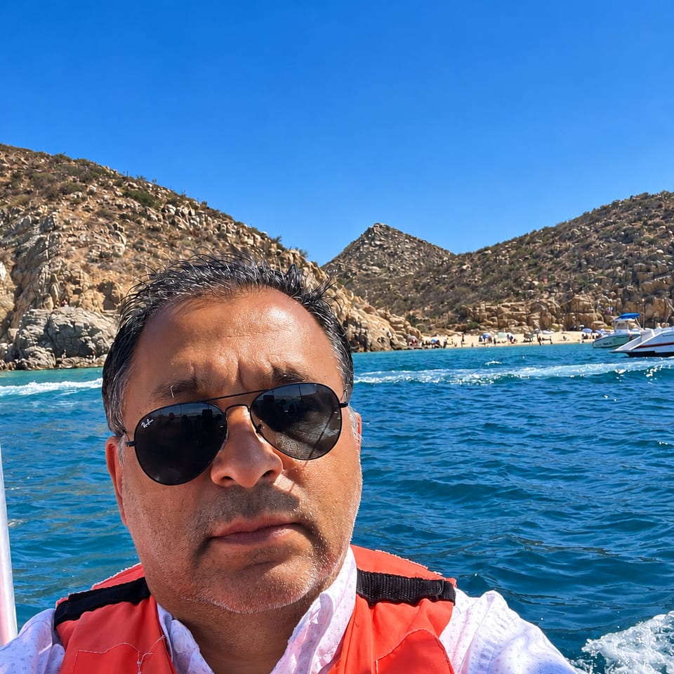 Man wearing a life jacket on a boat near a rocky coast