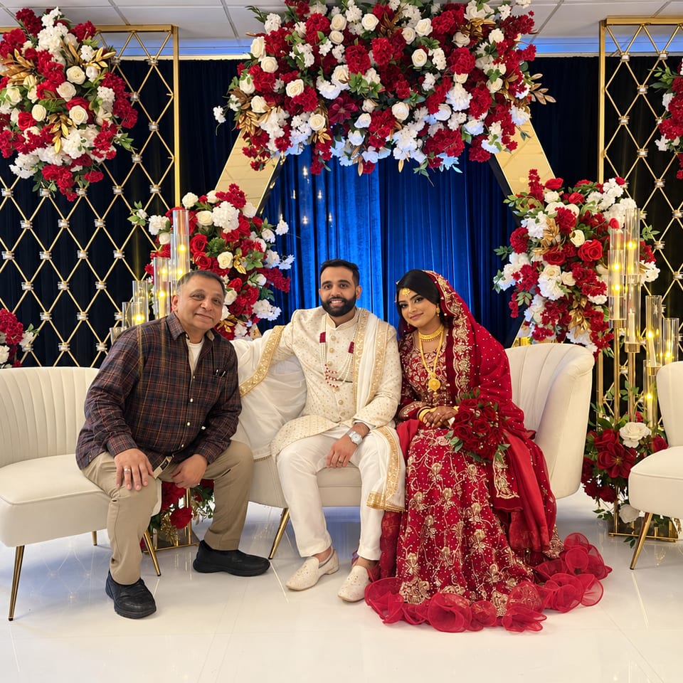 Three wedding guests seated before red and white flowers