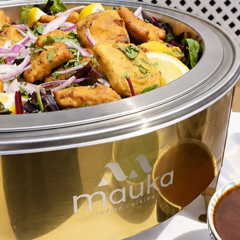 Golden fried pieces garnished with onion and herbs in a gold Mauka serving dish