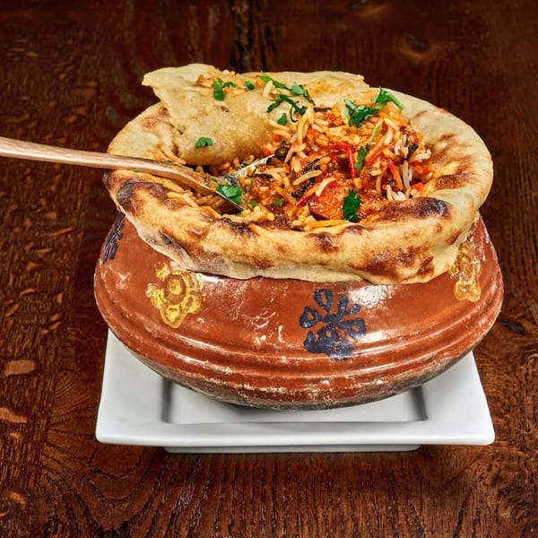 Mauka Indian Cuisine's chicken biryani, a flavorful rice dish with chicken, spices, and herbs, served in a clay pot.