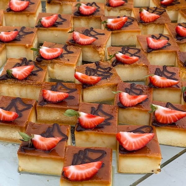 Rows of square Indian desserts topped with chocolate drizzle and a strawberry slice.
